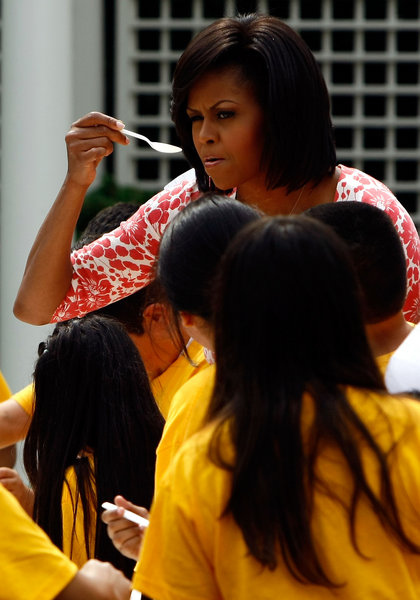 U.S. first lady Michelle Obama tastes a salad made from freshly harvested vegetables from the White House Kitchen Garden with students from Bancroft Elementary School on the South Lawn of the White House June 16, 2009 in Washington, DC. The first lady then sat down to a meal with the children including the lettuce and snap peas harvested from the garden to focus attention on health and nutrition. [CFP]