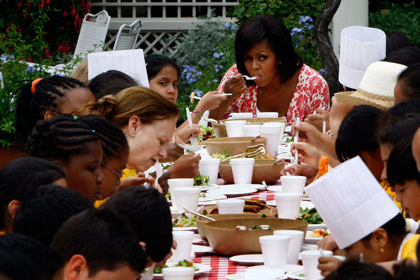 U.S. first lady Michelle Obama sits down for a meal with students from Bancroft Elementary School that included vegetables from the White House Kitchen Garden at the White House June 16, 2009 in Washington, DC. The first lady earlier harvested lettuce and snap peas from the garden to focus attention on health and nutrition. [CFP]