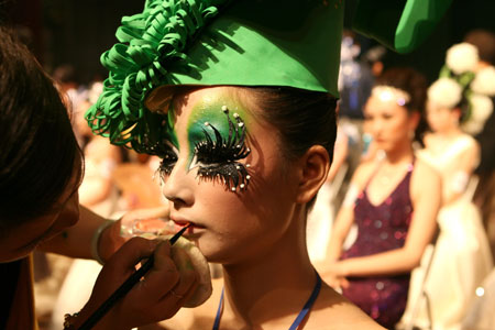 A contestant makes up for a model during an image design competition held in north China's Tianjin, June 16, 2009. More than 230 contestants took part in the competition here Tuesday, during which an environment-friendly concept was advocated.[Wei Xiaoming/Xinhua]