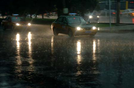 Taxis are seen in the heavy rain in Beijing, China, June 16, 2009. Local authority released a yellow alert for lightings on Tuesday. [Gong Lei/Xinhua] 