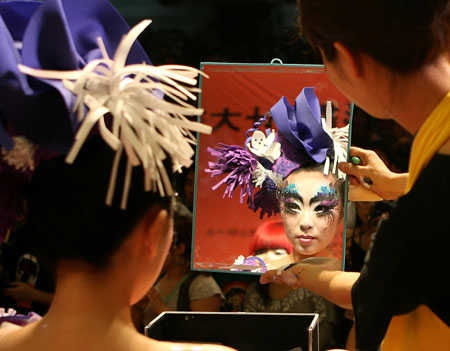 A contestant makes up for a model during an image design competition held in north China's Tianjin, June 16, 2009. More than 230 contestants took part in the competition here Tuesday, during which an environment-friendly concept was advocated.