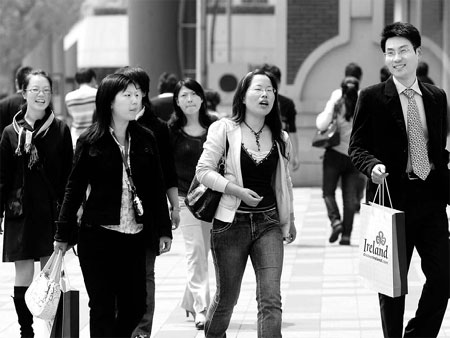 People walk on Nanjing Xilu, one of the busiest streets in Shanghai. China's most populous city announced detailed rules on Wednesday to allow some holders of temporary residency permits to become permanent residents, a move that is designed to attract talents but that was lambasted by some people as being discriminatory against migrant workers. [Photo: China Daily]