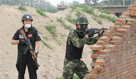 A special police member (L) and an armed policeman take part in an anti-terror drill in Zhuozhou, north China's Hebei Province, on June 17, 2009. The drill held here on Wednesday was the last part of the 'Great Wall-6' anti-terror exercise. The exercise, composing of a series of specialized drills, was carried out in June in north China's Inner Mongolia Autonomous Region, Shanxi and Hebei provinces to test the capabilities of the regions to combat terrorism and deal with emergencies. [Zhu Feng/Xinhua]
