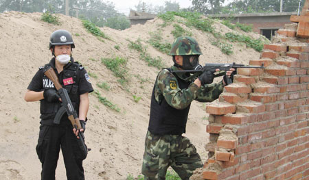 A special police member (L) and an armed policeman take part in an anti-terror drill in Zhuozhou, north China's Hebei Province, on June 17, 2009. The drill held here on Wednesday was the last part of the 'Great Wall-6' anti-terror exercise. The exercise, composing of a series of specialized drills, was carried out in June in north China's Inner Mongolia Autonomous Region, Shanxi and Hebei provinces to test the capabilities of the regions to combat terrorism and deal with emergencies. [Xinhua]