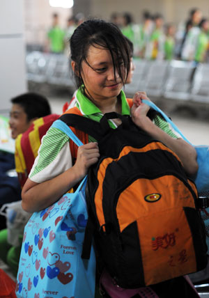 Meng Dan, a student of Sangping Middle School of Wenchuan County, southwest China's Sichuan Province, carries four bags on her shoulder at the waiting room of the Guangzhou Railway Station in Guangzhou, capital of south China's Guangdong Province, June 17, 2009.[Liu Dawei/Xinhua]