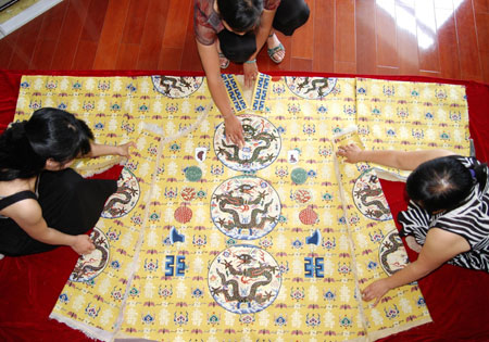 Three brocade embroideresses patch up the restituted ceremonial robes for the royalty of the Ming Dynasty (1368-1644) in Suzhou City, east China's Jiangsu Province, June 17, 2009. A workshop has successfully replicated the emperor's ceremonial robe, unearthed from the Dingling Maosoleum of Emperor Wanli in Beijing. It entails 6 kg of color silk threads, 100,000 meters of gold threads and over 6,000 peacock plumes. (Xinhua Photo) 