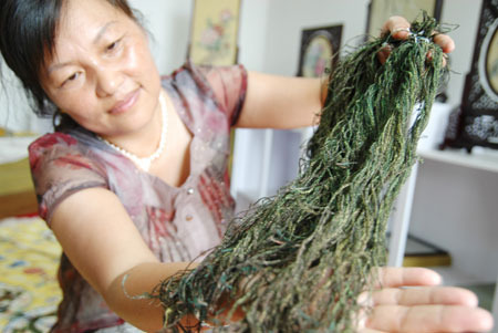 A brocade embroideress shows the peacock plume threads applied to the restituted ceremonial robes for the royalty of the Ming Dynasty (1368-1644) in Suzhou City, east China's Jiangsu Province, June 17, 2009.