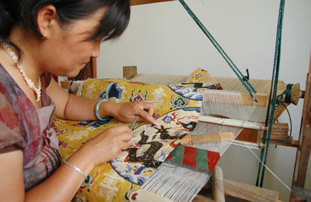  A brocade embroideress puts the final embellishment to the restituted ceremonial robes for the royalty of the Ming Dynasty (1368-1644), in Suzhou City, east China's Jiangsu Province, June 17, 2009. 