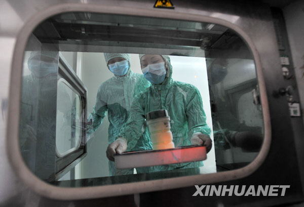 The researchers pass the container with virus strains of the influenza A/H1NI for cultivation of its vaccination through an obturator onto laboratory at the other side at the Wuhan Institute of Biological Products in Wuhan, central China's Hubei Province, June 17, 2009.[Zhou Chao/Xinhua]