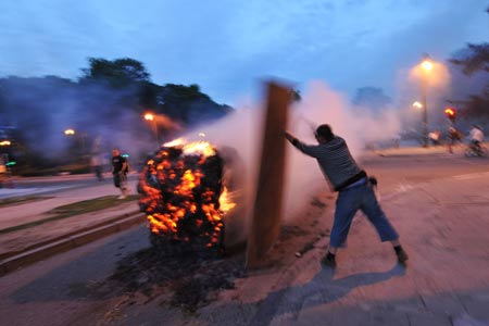 A protestor puts a board into fired haystack during the protest for a fair milk price outside the European Union headquarters in Brussels, capital of Belgium, on late June 18, 2009. [Wu Wei/Xinhua]