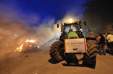 Protestors set fire to haystack during the protest for a fair milk price outside the European Union headquarters in Brussels, capital of Belgium, on late June 18, 2009.[Wu Wei/Xinhua]