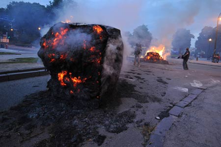 Protestors set fire to haystack during the protest for a fair milk price outside the European Union headquarters in Brussels, capital of Belgium, on late June 18, 2009. [Wu Wei/Xinhua]