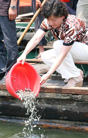 A citizen releases fish fry into the water by the Chunshen Lake in Suzhou City of east China's Jiangsu Province, June 18, 2009. [Wang Jianzhong/Xinhua]