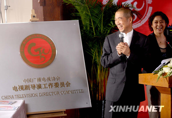Famous actor and director Zhang Guoli (L) smiling at the board with the name 'China TV Director Committee'