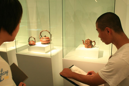 A student paints from a zisha (purple clay) teapot on display in the National Art Museum of China in Beijing, China, June 20, 2009. (Xinhua/Ding Huanxin) 