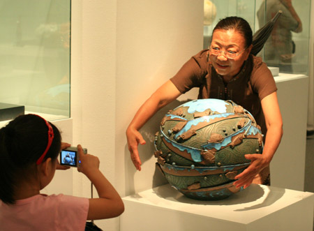 A citizen &apos;embraces&apos; the ceramic globe on display in the National Art Museum of China in Beijing, China, June 20, 2009. (Xinhua/Ding Huanxin)