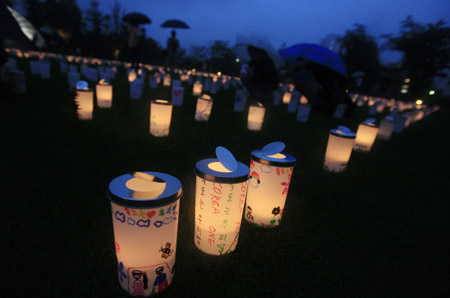 Plastic cups with candles in are set during the Candle Night campaign to call for saving the electricity with the lights off in Roppongi in Tokyo, capital of Japan, June 21, 2009. (Xinhua/Ren Zhenglai)