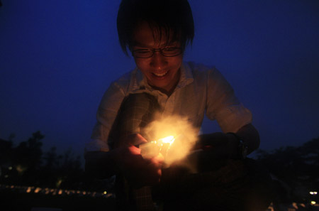 A man lightens a candle to put it into a plastic cup during the Candle Night campaign to call for saving the electricity with the lights off in Roppongi in Tokyo, capital of Japan, June 21, 2009. (Xinhua/Ren Zhenglai)