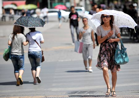 People holding umbrellas walk on a street in Yinchuan City, capital of northwest China's Ningxia Hui Autonomous Region, June 24, 2009. China is still on high temperature alert Thursday, as the heat wave that has hit many northern and western parts continued.[Xinhua]