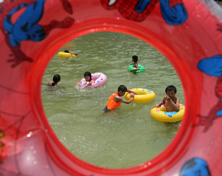 Chinese kids play water inside a swimming pool against a heatwave of over 37 degrees Celsius at Mengcheng County in east China's Anhui Province, June 25, 2009. [Xinhua]