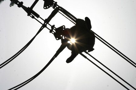 An employee of the local power company checks high-voltage power transmitting cables in Chaohu City in east China's Anhui Province, June 24, 2009, as a heatwave of over 35 degrees Celsius sweeps across the area. [Xinhua]