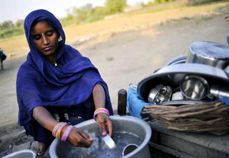 An Indian woman washes containers with spare water on the outskirts of southern New Delhi, captial of India, June 25, 2009. Searing heat wave continued to scorch the plains of north India with temperatures of its capital remained above 42 degrees Celsius for days. According to meteorological offcials, the extreme heat conditions would probably persist for a period of time due to delayed monsoon. [Xinhua]