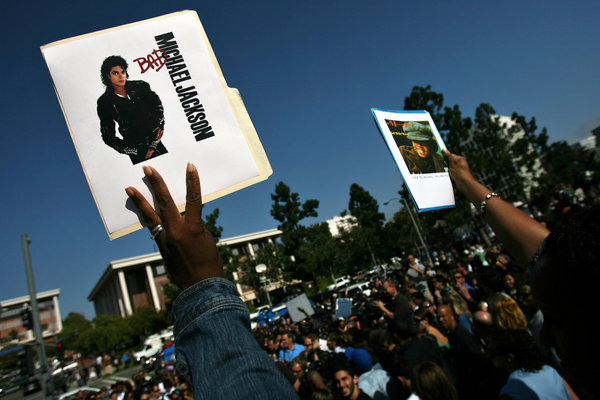 People hold up Michael Jackson pictures as media and spectators wait for a news conference about Michael Jackson's death at UCLA Medical Plaza June 25, 2009 in Los Angeles, California.