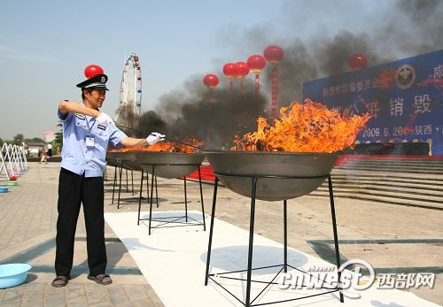 An anti-drug police officer burns drugs on a square in Xianyang City, Shaanxi Province, on June 26, 2009. The province has seized more than 200 kilograms of heroin, 14 kilograms of crystal methamphetamines and 25 kilograms of opium since 2005. [Photo: cnwest.com]
