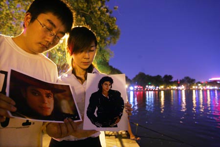 Two Chinese fans hold pictures of Michael Jackson as they attend a night gathering to mourn for the late U.S. megastar Michael Jackson, in Beijing, China, June 26, 2009.