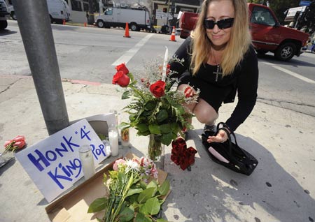 A woman places flowers at a makeshift memorial across the street from the County of Los Angeles Department of Coroner facility in Los Angeles June 26, 2009, where Michael Jackson's body was carried to on Thursday by helicopter.