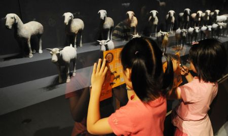 Two little girls take notes while watching the excavated cultural relics from the Mausoleum of Emperor Jingdi of the Western Han Dynasty (202 BC - 8 AD), during the Smiling Color Clay Figurines special exhibition of cultural relics from the underground kingdom of Emperor Jingdi who reigned from 156 BC to 141 BC, which opens in Taipei, southeast China's Taiwan, June 26, 2009.