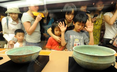 Visitors gaze at a couple of colorful clay utensils excavated from the Mausoleum of Emperor Jingdi of the Western Han Dynasty (202 BC - 8 AD), during the Smiling Color Clay Figurines special exhibition of cultural relics from the underground kingdom of Emperor Jingdi who reigned from 156 BC to 141 BC, which opens in Taipei, southeast China's Taiwan, June 26, 2009.