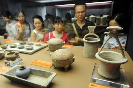 Visitors gaze at a full range of clay utensils excavated from the Mausoleum of Emperor Jingdi of the Western Han Dynasty (202 BC - 8 AD), during the Smiling Color Clay Figurines special exhibition of cultural relics from the underground kingdom of Emperor Jingdi who reigned from 156 BC to 141 BC, which opens in Taipei, southeast China's Taiwan, June 26, 2009. 