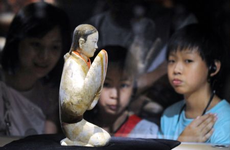 Visitors gaze at a colorful clay figurine of a female servant in kneeling posture excavated from the Mausoleum of Emperor Jingdi of the Western Han Dynasty (202 BC - 8 AD), during the Smiling Color Clay Figurines special exhibition of cultural relics from the underground kingdom of Emperor Jingdi who reigned from 156 BC to 141 BC, which opens in Taipei, southeast China's Taiwan, June 26, 2009.