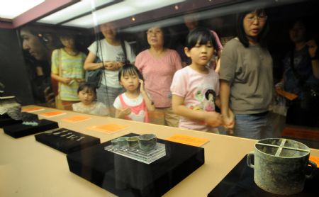 Visitors watch a full range of colorful clay wares excavated from the Mausoleum of Emperor Jingdi of the Western Han Dynasty (202 BC - 8 AD), during the Smiling Color Clay Figurines special exhibition of cultural relics from the underground kingdom of Emperor Jingdi who reigned from 156 BC to 141 BC, which opens in Taipei, southeast China's Taiwan, June 26, 2009. 