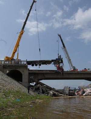 Cranes work at Xida Bridge in Tieli, a city of notheast China's Heilongjiang Province, June 29, 2009. Part of Xida Bridge, a parallel road bridge spanning Hulan River of Tieli, collapsed early Monday, causing at least one dead, and 8 vehicles plunged into the water below. (Xinhua/Wang Song)
