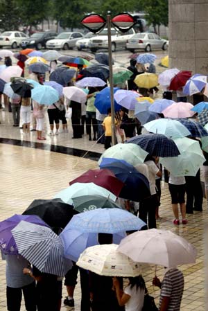 Local citizens queue up against rain for their admissions into the Liaoning Provincial Museum to watch the National Treasures -- Exposition of Cultural Relics under Collection of the National Museum of China, in Shenyang, northeast China's Liaoning Province, June 28, 2009. The exposition, which is open to the public gratis and will last until August 31, presents a total of 78 pieces of national treasure-level cultural relics dated back from the paleolithic period to the Tang Dynasty (618-907), of which the top-notch cultural relics accounting for 72 percent of the total exhibits. (Xinhua/Zhang Wenkui)