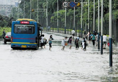 Passengers wade through a flooded street onto the sidewalk in China's Chongqing Municipality June 27, 2009. [Chongqing Economic Times]