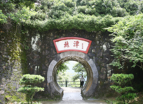 A visitor poses for a photo in Longtan scenery zone of Jinggang Mountain in Jiangxi on June 20, 2009. [CRI] 