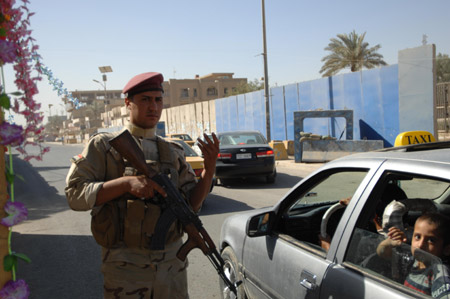 An Iraqi soldier guides a car through a check point in Baghdad, capital of Iraq, July 1, 2009, the first day after U.S. combat troops withdrawing from major cities in Iraq. (Xinhua/Gao Shan)