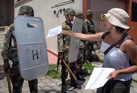 Supporter of Honduras' President Manuel Zelaya distributes slogans to a police during a rally in Tegucigalpa, capital of Honduras, July 1, 2009. Honduras' President Zelaya said he will postpone his return to Honduras 72 hours to the weekend, instead of Thursday, as originally planned. (Xinhua/David De La Paz)