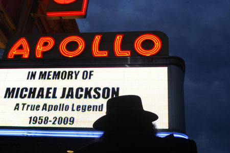 A man stands in front of a marquee displaying a memorial message during the Michael Jackson public memorial at the Apollo Theater in New York July 1, 2009. The Apollo will welcome fans 600 at a time to enter the theater to pay their respects, hear Jackson's music spun by New York DJs and see a a video tribute to the late pop star. 