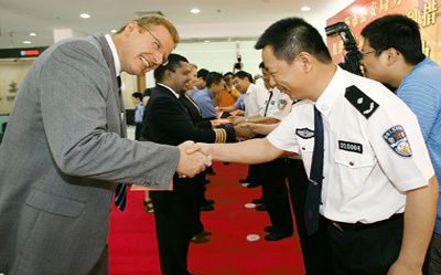 Germany's Walter Keller, chief financial officer of Celanese (China) Holding Co, shakes hands with an officer of the Shanghai Exit-Entry Administration as he receives his new residence permit yesterday. [Shanghai Daily]