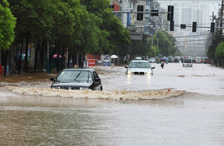 Vehicles move on the water-logging road in Pingxiang City, southeast China's Jiangxi Province, July 2, 2009. A heavy rain hit Pingxiang City from Wednesday night to Thursday morning. The city faced frequent thunder storm recently. [Xinhua]