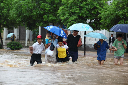Pedestrians move on the water-logging road in Pingxiang City, southeast China's Jiangxi Province, July 2, 2009. A heavy rain hit Pingxiang City from Wednesday night to Thursday morning. The city faced frequent thunder storm recently. [Xinhua]