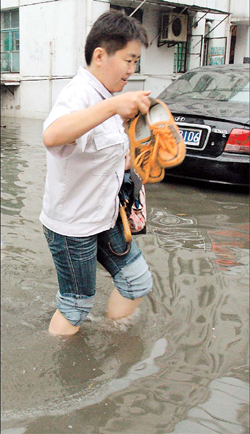 A resident wades along a flooded street in Chuansha Town in Shanghai's Pudong New Area yesterday afternoon after a downpour. The heaviest rainstorm so far this summer flooded streets, homes and shops in Chuansha, and caused flight cancellations and the disruption of ferry services in other parts of the city. [Shanghai Daily]