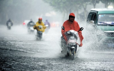 Pedestrians and vehicles wade along a flooded street in Shanghai yesterday afternoon after a downpour. An 'orange' alert was declared, the second highest on a three-level scale. [Shanghai Morning Post]