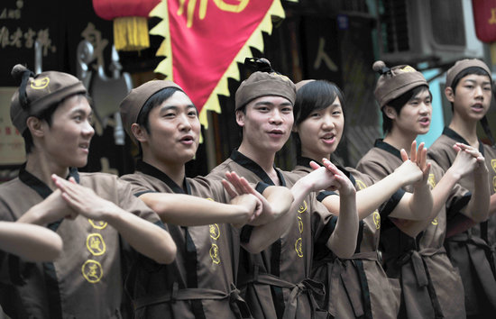 Waiters in ancient costumes at a restaurant featuring martial arts themes attract visitors as the restaurant opens in Chengdu, capital of southwest China's Sichuan Province on Thursday, July 2, 2009. [CFP]