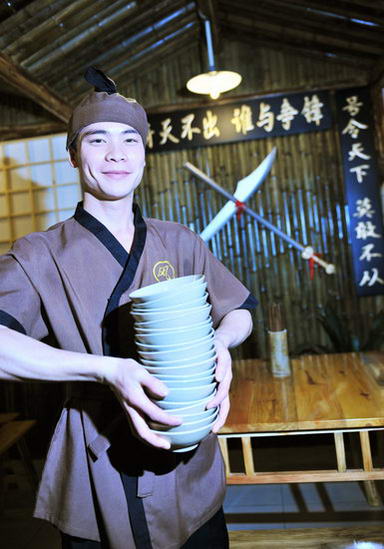 A waiter in ancient costume at a restaurant featuring martial arts themes attracts visitors as the restaurant opens in Chengdu, capital of southwest China's Sichuan Province on Thursday, July 2, 2009. [CFP]