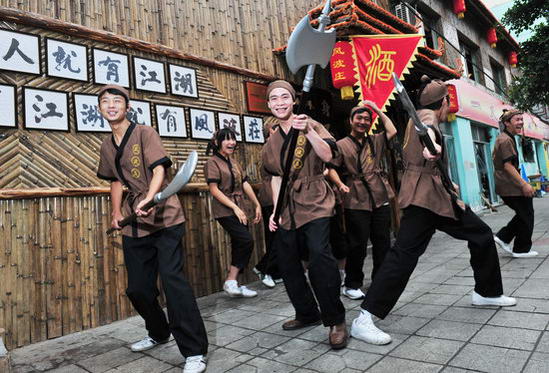 Waiters in ancient costumes at a restaurant featuring martial arts themes attract visitors as the restaurant opens in Chengdu, capital of southwest China's Sichuan Province on Thursday, July 2, 2009. [CFP]